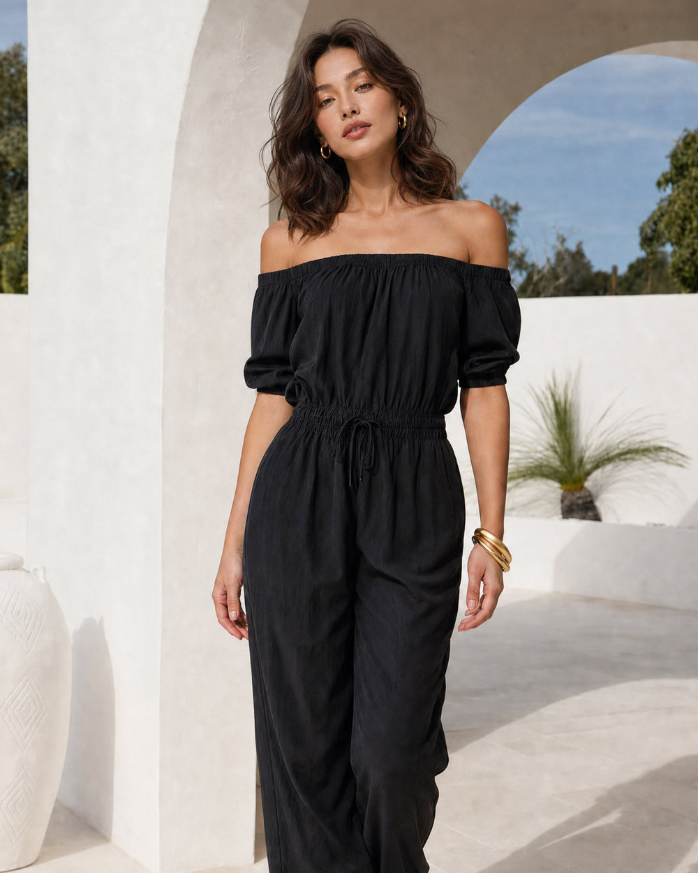 Czarny jumpsuit damski z odkrytymi ramionami, widok z przodu