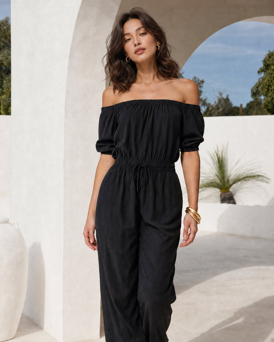 Czarny jumpsuit damski z odkrytymi ramionami, widok z przodu